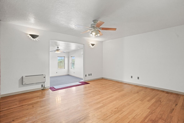 unfurnished living room with ceiling fan, baseboards, wood finished floors, and a textured ceiling