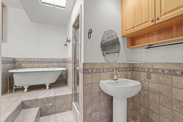 full bathroom with a stall shower, wainscoting, tile walls, a freestanding bath, and tile patterned flooring