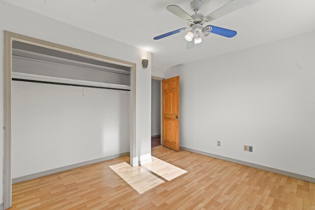 unfurnished bedroom with baseboards, wood finished floors, a closet, and ceiling fan