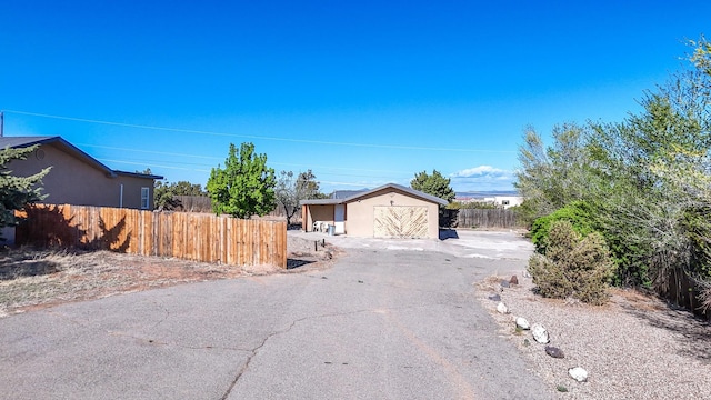 view of front of property featuring an outdoor structure, stucco siding, and fence