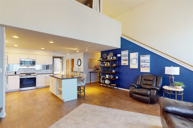 4715 Quemazon, Los Alamos, NM 87544 - kitchen featuring white cabinets, light wood finished floors, a kitchen breakfast bar, appliances with stainless steel finishes, and open floor plan