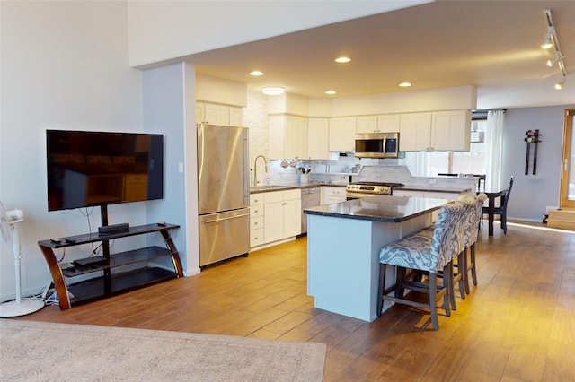 4715 Quemazon, Los Alamos, NM 87544 - kitchen with a kitchen breakfast bar, a sink, white cabinetry, wood-type flooring, and appliances with stainless steel finishes