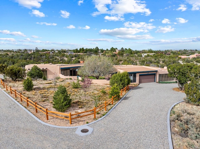 view of front of home with an attached garage, driveway, fence, and stucco siding