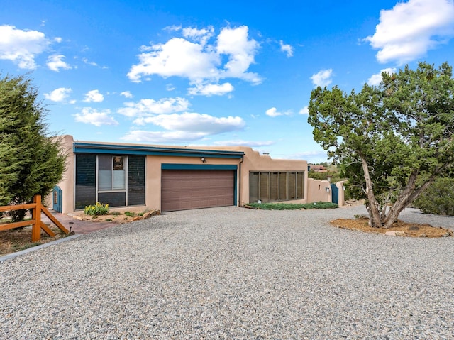 view of front of house with a garage, gravel driveway, and stucco siding