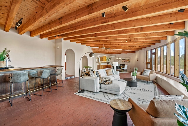 interior space with brick floor, wood ceiling, bar, arched walkways, and beam ceiling