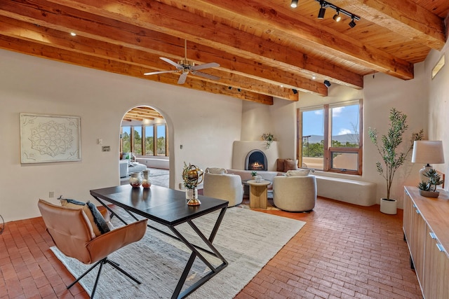 dining space with beam ceiling, brick floor, wooden ceiling, and arched walkways