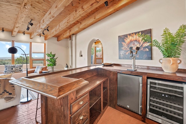 bar featuring freestanding refrigerator, beverage cooler, wooden ceiling, and brick floor