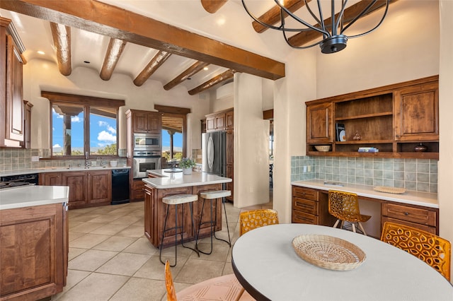 kitchen with tasteful backsplash, beamed ceiling, light countertops, a kitchen island, and appliances with stainless steel finishes