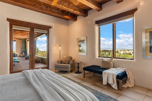 bedroom featuring beam ceiling, tile patterned floors, wood ceiling, and access to outside