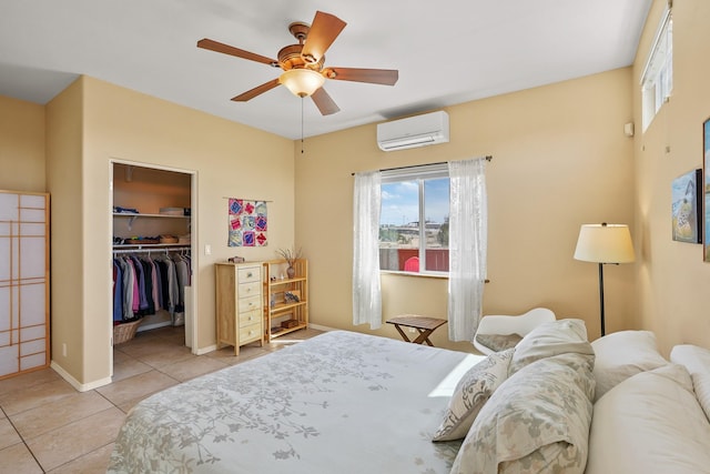 bedroom featuring a ceiling fan, a closet, a walk in closet, light tile patterned flooring, and a wall unit AC