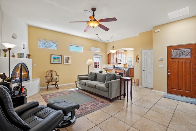 living area with an AC wall unit, baseboards, a ceiling fan, and light tile patterned floors