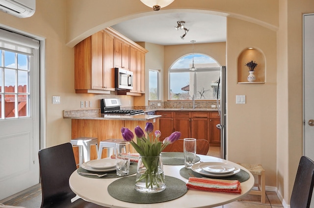 dining room with a wall mounted AC, arched walkways, and a healthy amount of sunlight