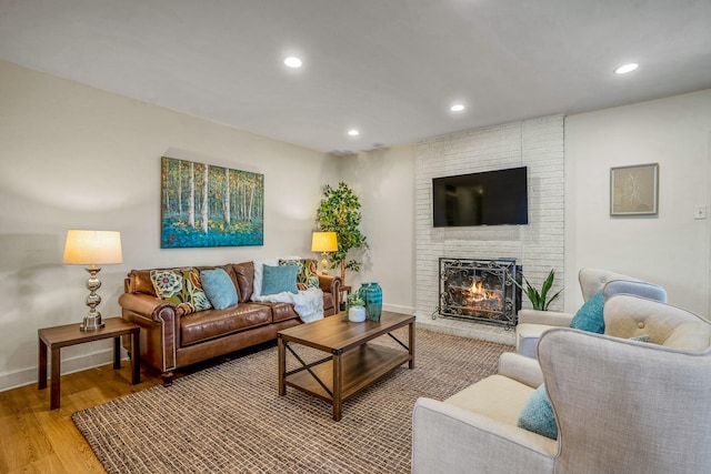 living area featuring baseboards, a brick fireplace, light wood finished floors, and recessed lighting