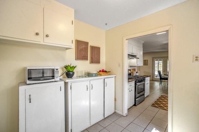 kitchen featuring light tile patterned floors, gas range, a toaster, light countertops, and under cabinet range hood
