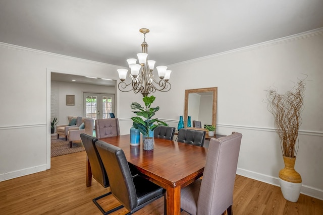 dining space with french doors, light wood-type flooring, baseboards, an inviting chandelier, and crown molding