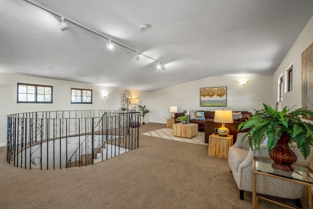 sitting room featuring vaulted ceiling, rail lighting, an upstairs landing, carpet floors, and baseboards