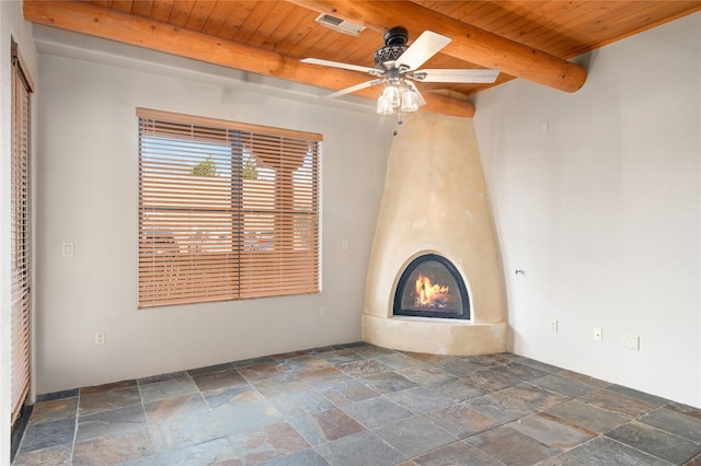 1405 Vegas Verdes Unit 136, Santa Fe, NM 87507 - unfurnished living room featuring stone tile floors, wood ceiling with exposed beams, ceiling fan, and a large fireplace