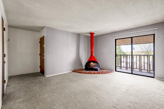 unfurnished living room featuring carpet floors, a wood stove, a textured ceiling, and baseboards