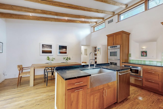 kitchen with double oven, a high ceiling, dark countertops, visible vents, and a sink
