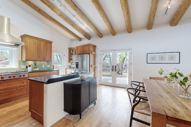 kitchen featuring stainless steel appliances, french doors, a sink, wall chimney exhaust hood, and light wood-style flooring