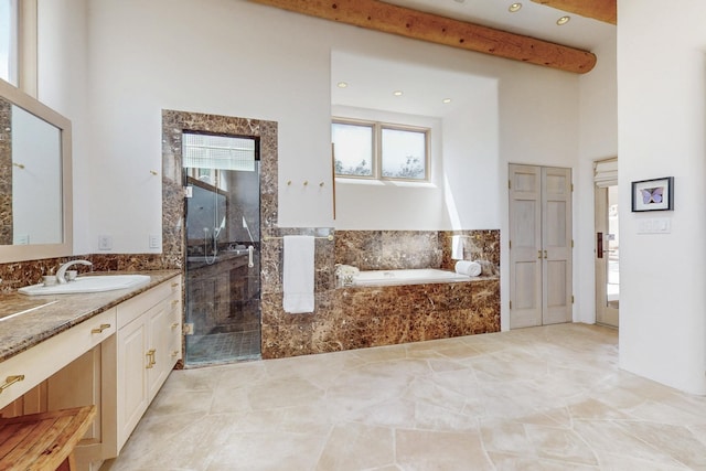 full bath with a stall shower, a towering ceiling, beamed ceiling, a garden tub, and vanity