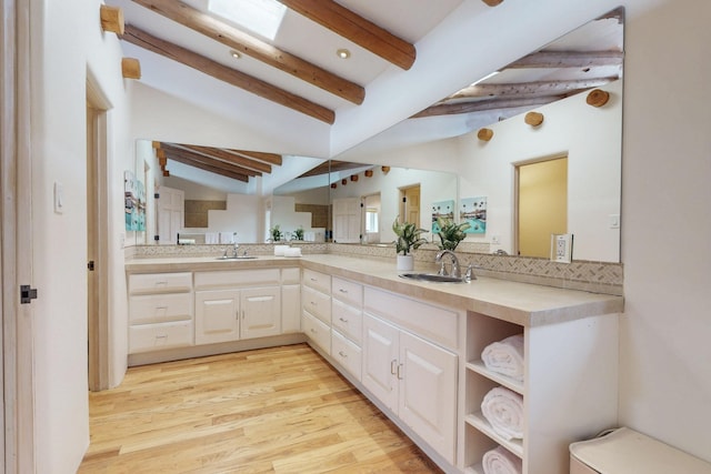 full bath featuring lofted ceiling with beams, wood finished floors, a sink, and double vanity