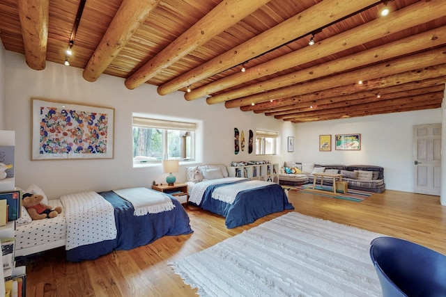 bedroom featuring track lighting, wood finished floors, and beam ceiling