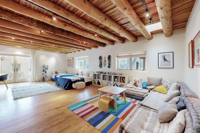 bedroom featuring beamed ceiling, french doors, and wood finished floors