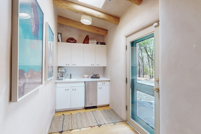 kitchen with white cabinets, light countertops, light wood finished floors, and a sink