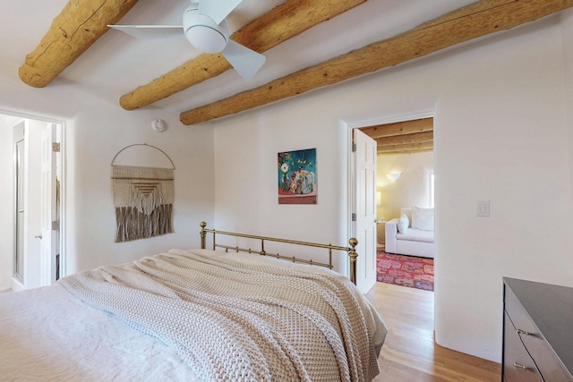 bedroom with a ceiling fan, beamed ceiling, and light wood-style flooring