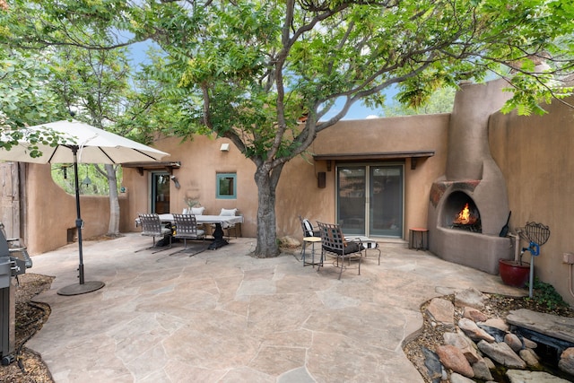 view of patio featuring outdoor dining area and a warm lit fireplace