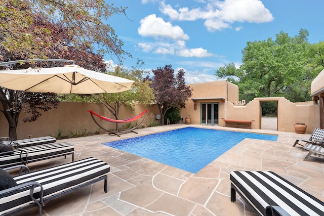 view of swimming pool with fence, a fenced in pool, french doors, and a patio