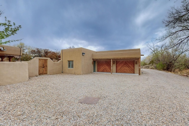 exterior space featuring a gate, driveway, an attached garage, fence, and stucco siding