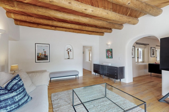 living room featuring light wood finished floors, wooden ceiling, beam ceiling, and arched walkways