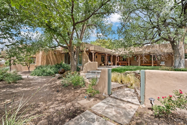 southwest-style home featuring a gate, stucco siding, and fence private yard