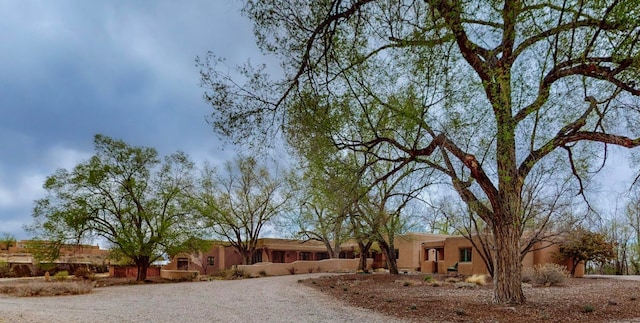 view of front facade featuring gravel driveway and stucco siding