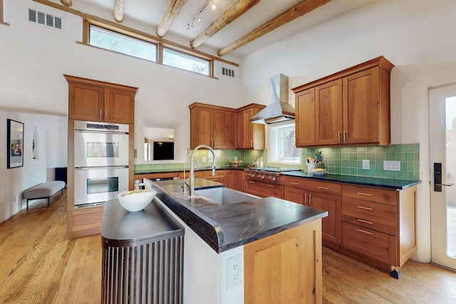 kitchen with wall chimney exhaust hood, dark countertops, visible vents, and appliances with stainless steel finishes