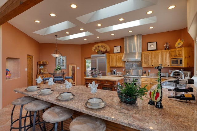 21 Canada Vista Dr, Sandia Park, NM 87047 - kitchen with wall chimney exhaust hood, recessed lighting, a skylight, built in appliances, and a breakfast bar