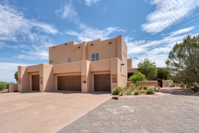 21 Canada Vista Dr, Sandia Park, NM 87047 - pueblo revival-style home featuring a garage, driveway, fence, and stucco siding