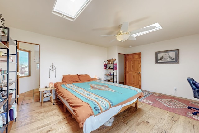 bedroom featuring wood finished floors, a skylight, and a ceiling fan