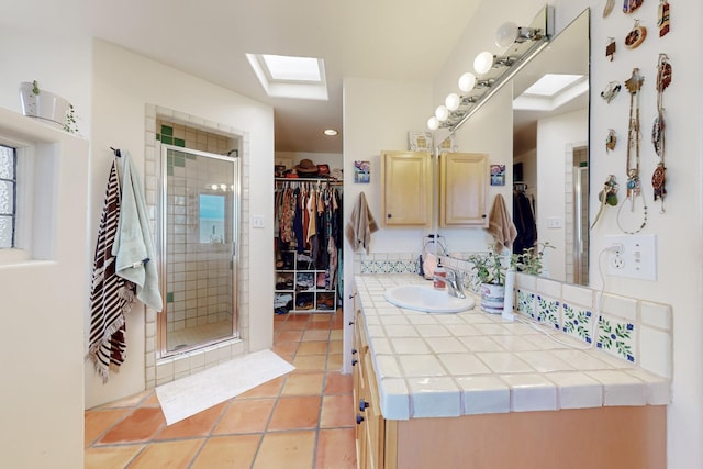 full bathroom with a spacious closet, a skylight, tile patterned flooring, a shower stall, and vanity