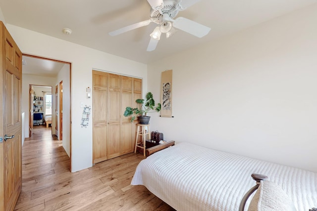 bedroom with a ceiling fan, light wood-style floors, and a closet