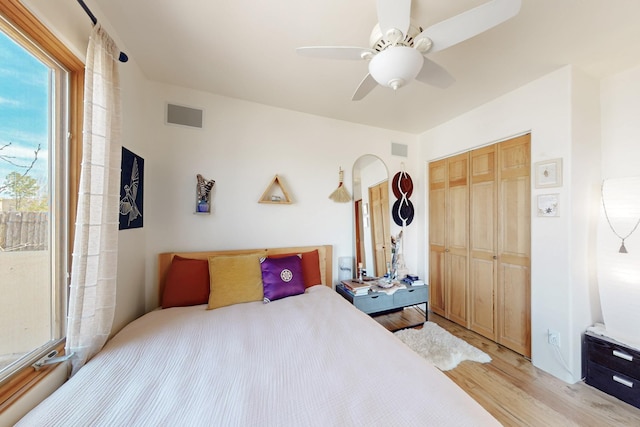 bedroom with ceiling fan, visible vents, light wood-style floors, and a closet