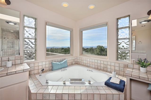 full bathroom featuring a garden tub, a healthy amount of sunlight, and vanity