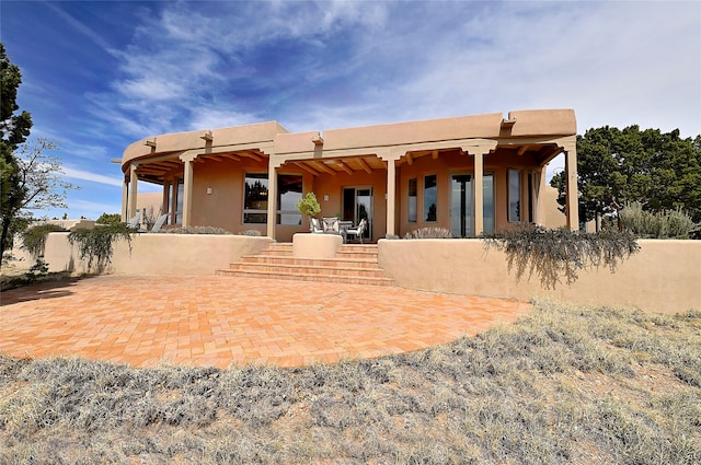 rear view of property with stucco siding and a patio