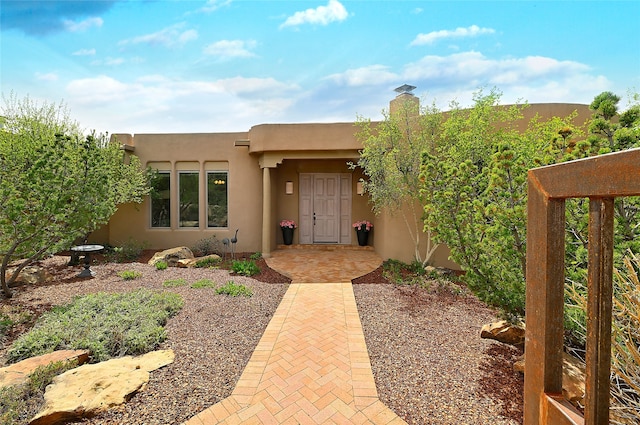 property entrance with a chimney and stucco siding