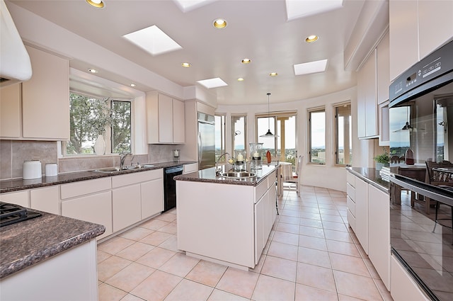 kitchen with a sink, recessed lighting, a skylight, decorative backsplash, and black appliances