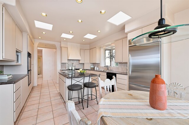 kitchen featuring recessed lighting, backsplash, a breakfast bar, built in refrigerator, and a center island