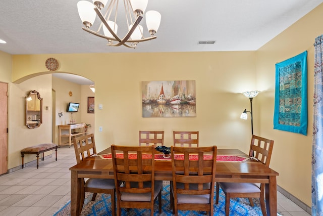 dining area featuring light tile patterned flooring, arched walkways, an inviting chandelier, baseboards, and visible vents