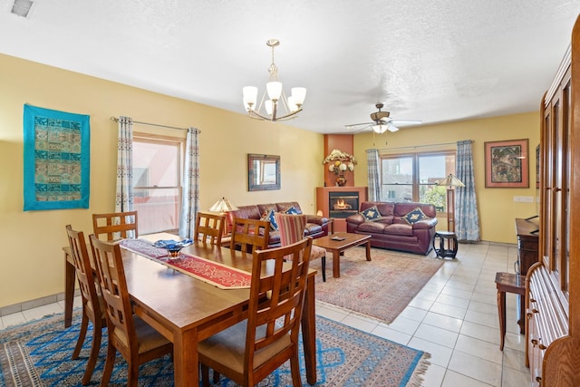 dining area with a textured ceiling, light tile patterned floors, and ceiling fan with notable chandelier